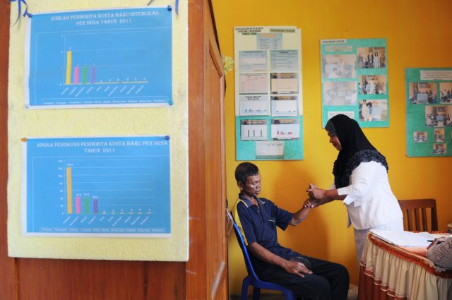Een vrouwelijke arts uit Indonesie onderzoekt een man op symptomen van lepra